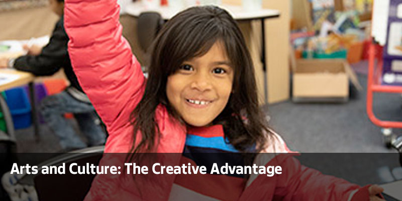 Little girl holds her hand up in the classroom. Arts and Culture: The Creative Advantage